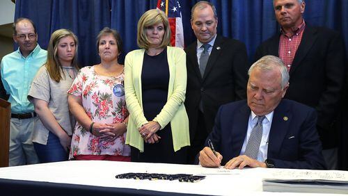 Gov. Nathan Deal signs House Bill 673 prohibiting Georgia motorists from handling their cellphones while driving as the families of five nursing students who died when they were struck by a semi on I-16 look on during a emotional ceremony at the Statesboro-Bullock County Airport on Tuesday, May 2, 2018, in Statesboro. Curtis Compton/ccompton@ajc.com