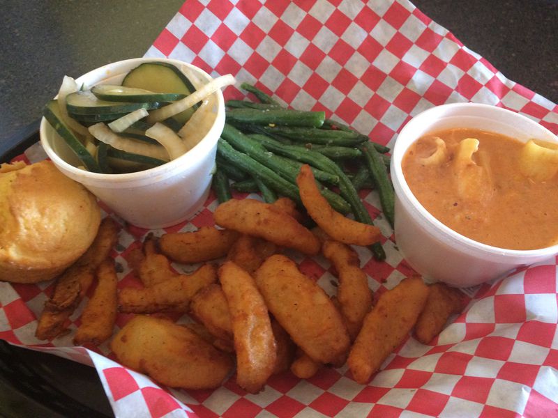 At Sam’s BBQ-1 in east Cobb, you can order a basket of sides. This sampler includes tomato and onion salad, flash-fried green beans, Redneck Lasagna (a mixture of Brunswick stew and mac and cheese), batter-fried onion petals and a corn muffin. CONTRIBUTED BY WENDELL BROCK