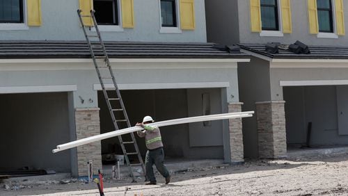 A construction worker carries pipe at the a Florida development by Pulte Homes last year. (Amy Beth Bennett/Sun Sentinel/TNS)