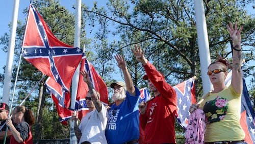 Pro-Confederate flag supporters at a protest at Stone Mountain last November offer a Klan “salute” at the base of the mountain trail. Organizers for the rally initially denied connections to white extremists, but photos posted later to social media showed them in clothing with Klan symbols. KENT D. JOHNSON / KDJOHNSON@AJC.COM