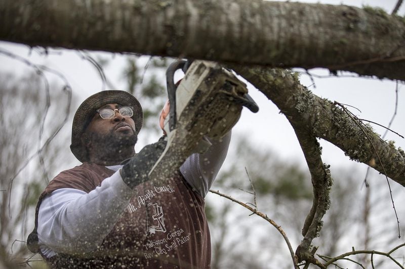 03/04/2019 — Talbotton, Georgia — Reginald Leonard uses a chain saw to cut away at a fallen tree in the driveway of a family friends house along George W. Town Road in Talbotton, Monday, March 4, 2019. Keith Stellman, head forecaster for the National Weather Service, said during the presser that the path of destruction in the town looked to be caused by an EF2 tornado, although that wasn’t confirmed during the governor’s tour. ALYSSA POINTER/ALYSSA.POINTER@AJC.COM