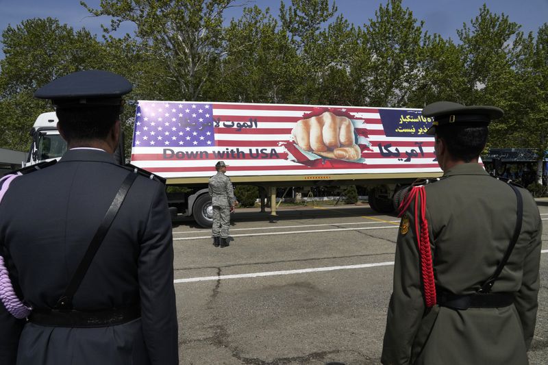 FILE - An anti-U.S. banner is carried on a truck during Army Day parade at a military base in northern Tehran, Iran, April 17, 2024. This month's unprecedented direct attacks between Iran and Israel are revealing deeper insights into both militaries. Experts say Friday's apparent precision strike by Israel deep into Iran demonstrated Israel's military dominance on almost all fronts. (AP Photo/Vahid Salemi, File)