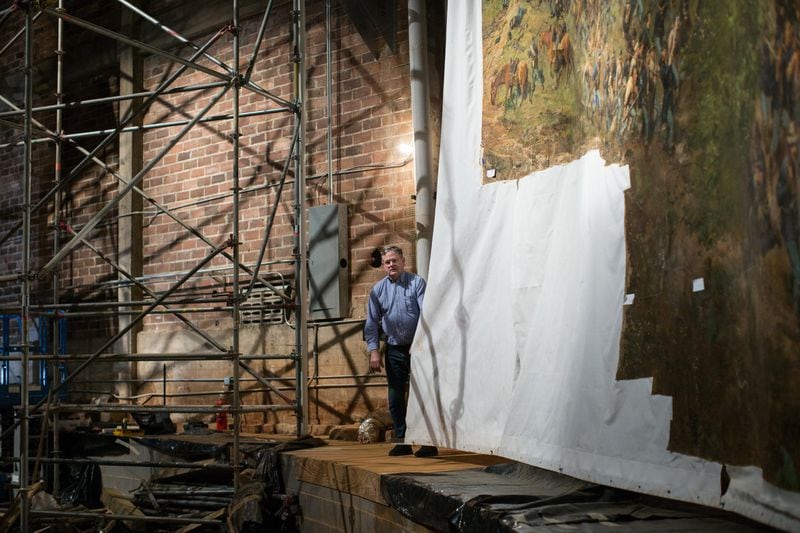 Conservator Thomas Schoeller, from Munich, holds on to the edge of the canvas that has been glued to the top and bottom edges of “The Battle of Atlanta.” Technicians moving the painting to a new home at the Atlanta History Center will handle the painting by those edges. BRANDEN CAMP / SPECIAL