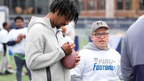 LSU quarterback Jayden Daniels signs a football for a young athlete during an NFL Football Play Football Prospect Clinic with Special Olympics athletes, Wednesday, April 24, 2024 in Detroit. (AP Photo/Carlos Osorio)
