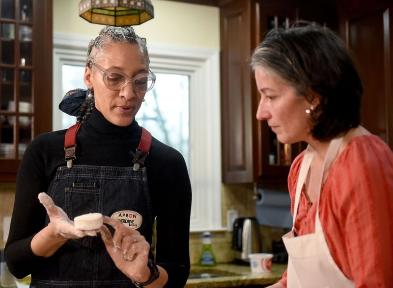 Carla Hall (left) shows Ligaya Figueras (right) the texture of a good biscuit. Ligaya hosted Hall and food expert Chadwick Boyd at her home, where the two shared tips with Ligaya on how to make the best biscuits. RYON HORNE / RHORNE@AJC.COM