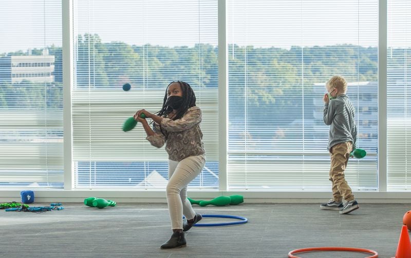 Inspire Brands, the Sandy Springs-based restaurant company, offers options to their employees who want to get back to work at the office.  The company opened their Young Achievers Academy on the 11th floor of their office building where Elsie Busieney, 11, left, takes her turn at bat while 6-year-old Whitaker Fuller enjoys the view during activity time.   Employees, who choose to come in to work, can also bring their children for virtual learning school days, art actives, exercising and social interactions.  (Jenni Girtman for The Atlanta Journal-Constitution)
