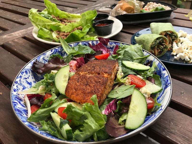 Eco Car Spa focuses on health-minded food. Options include blackened salmon salad (foreground), as well as a soy ginger lettuce wrap with ground beef, jerk chicken salad and a hummus wrap. LIGAYA FIGUERAS / LIGAYA.FIGUERAS@AJC.COM