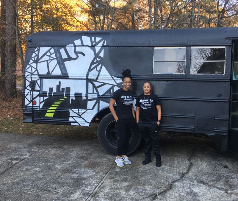Bridge of Light founder Torrie Everheart (L) and Ray Young pose in front of their Dignity Bus.