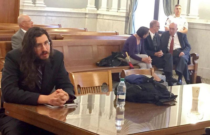 Michael Rotondo, left, sits during an eviction proceeding in Syracuse, N.Y., brought by his parents, Mark and Christina, of Camillus. The two parents confer with their lawyer, Anthony Adorante, in the court gallery behind. Rotondo told the judge Tuesday, May 22, 2018, he knows his parents want him out of their Camillus home, near Syracuse. But he argued he is entitled to six months more time.