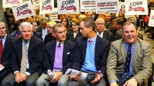 NOVEMBER 26, 2013 — Braves GM Frank Wren (from left), Braves Team President John Schuerholz, and Braves Executive Vice Presidents Derek Schiller and Mike Plant are backed by a show of support while sitting on the front row at the opening of the Cobb County Board of Commissioners meeting to vote on the new Braves stadium on Nov. 26, 2013, in Marietta. (Photo: Curtis Compton/ ccompton@ajc.com)