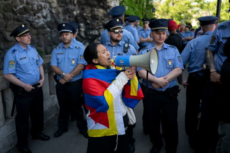 A Tibetan woman shouts into a loudspeaker against Chinese President Xi Jinping's visit, surrounded by Hungarian police in Gellert Hill, Budapest, Hungary on Thursday, May 9, 2024. (AP Photo/Denes Erdos)