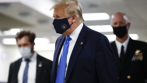 President Donald Trump wears a mask Saturday as he walks down the hallway during his visit to Walter Reed National Military Medical Center in Bethesda, Md. (AP Photo/Patrick Semansky)