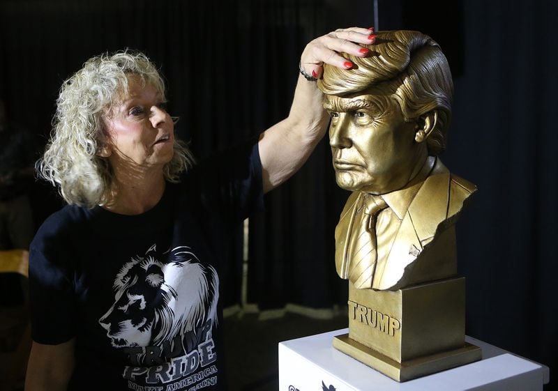 In this file photo, Debbie Dooley rubs the head of a Donald Trump statue "for good luck" at an Atlanta event. She is appealing to fellow Republicans to demonstrate at a GOP event where Trump was not invited. (Curtis Compton / The Atlanta Journal-Constitution)