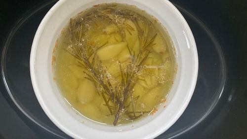 Garlic confit, whose recipe includes fresh rosemary, comes together easily in the slow cooker. The roasted garlic flavor makes any savory dish worthy of a holiday. (Kellie Hynes for The Atlanta Journal-Constitution)