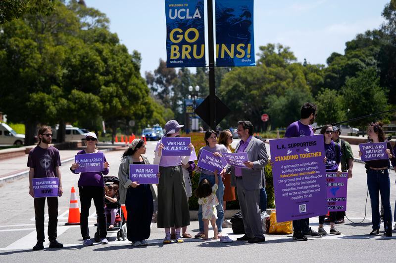Demonstrators hold signs on the UCLA campus, the morning after clashes between Pro-Israel and Pro-Palestinian groups, Wednesday, May 1, 2024, in Los Angeles. (AP Photo/Jae C. Hong)