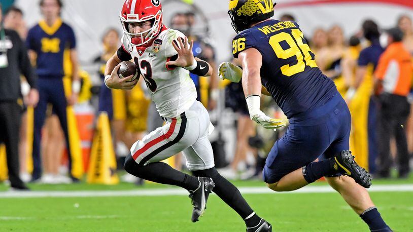 Georgia Bulldogs quarterback Stetson Bennett seems to strike a pose when in fact he's running away from Michigan Wolverines defensive lineman Julius Welschof during the college football's playoff semifinal. One more win, and he's a certified Georgia legend. (Hyosub Shin / Hyosub.Shin@ajc.com)