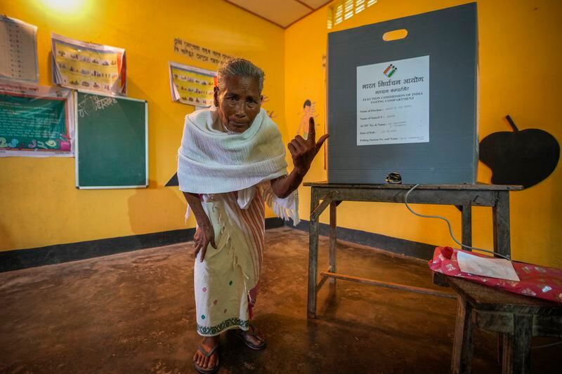 An elderly woman shows the indelible ink mark on her index finger after casting vote in a polling station during the third phase of general election on the outskirts of Guwahati, India, Tuesday, May 7, 2024. (AP Photo/Anupam Nath)
