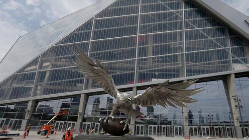 A man walks past a sculpture of a Falcon outside the entrance to Mercedes Benz Stadium, the new home of the Atlanta Falcons football team and the Atlanta United soccer team, Tuesday, July 25, 2017, in Atlanta. (AP Photo/John Bazemore)
