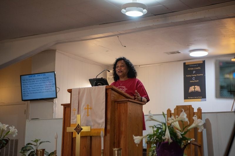 Peters Chapel AME Pastor Sherryl King reads from the Scriptures, the words cast on a screen beside her that the congregation purchased using a grant from Alter. (Photo Courtesy of Shereen Ragheb)