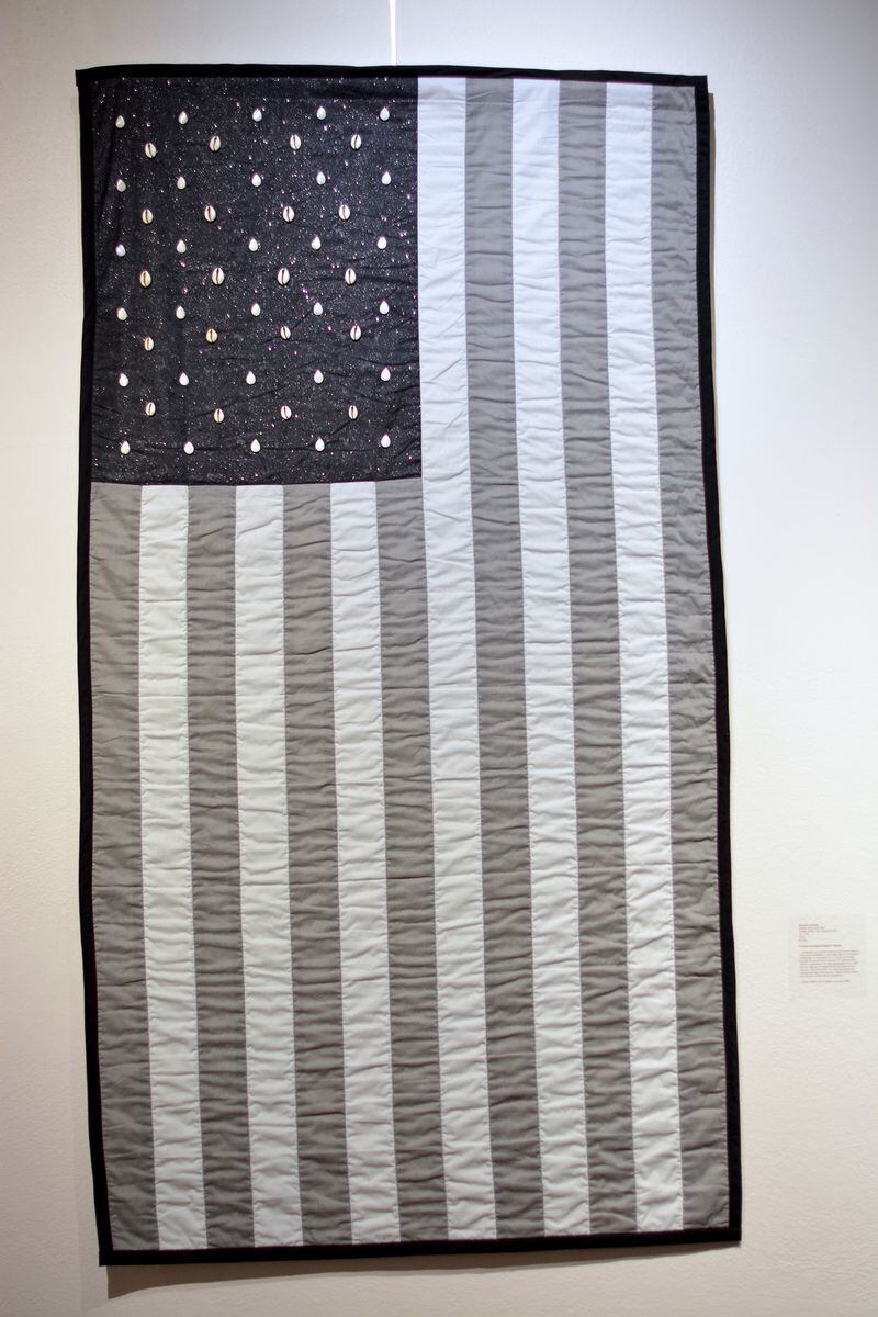 "Capital Gains" quilted black and gray American flag with cowrie shells for stars. Accompanied by an excerpt from David Walker's Appeal (1829), by Jerushia Graham.
Courtesy of Caroline Giddis
