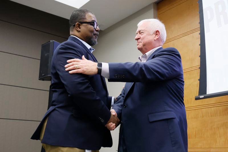 AJC editor-in-chief Leroy Chapman Jr. left, shakes hands with outgoing AJC editor Kevin Riley during the AJC Town Hall meeting at Cox Headquarters on Thursday, March 23, 2023, in Atlanta. (Miguel Martinez for the Atlanta Journal-Constitution)