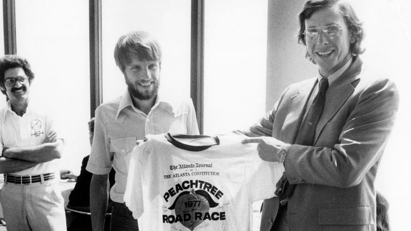 Members of the Atlanta Track Club present Jim Cox Kennedy the 1976 AJC Peachtree Road Race T-shirt