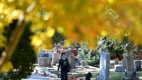 Kelly Carnes takes advantage of the fall weather to walk her dog Oliver at historic Oakland Cemetery on October 31, 2017, in Atlanta. Photo: Curtis Compton/ccompton@ajc.com