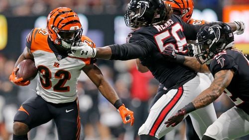 Cincinnati Bengals running back Mark Walton (32) is grabbed by Atlanta Falcons defensive end Steven Means (56) on a carry in the fourth quarter of the NFL Week 5 game between the Atlanta Falcons and the Cincinnati Bengals at Mercedes-Benz Stadium in Atlanta on Sunday, Sept. 30, 2018. The Bengals scored a touchdown in the final seconds of the fourth quarter to win 37-36.
