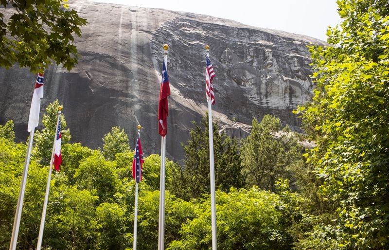 A collection of flags including those representing Georgia, the United States and the Confederacy fly at the base of Stone Mountain in Valor Park on Friday, May 26, 2023, in Stone Mountain, Georgia. The Confederate flag was recently moved from its previos location at the base of the walking trail. CHRISTINA MATACOTTA FOR THE ATLANTA JOURNAL-CONSTITUTION