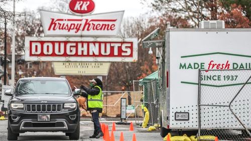 Lavenus Fulton hands over an order to a customer at the pop-up Krispy Kreme that opened Tuesday on the site of the twice-burned location on Ponce de Leon Avenue.