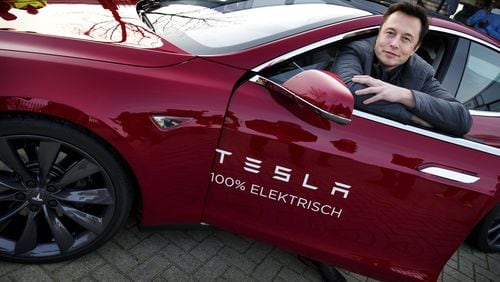 Elon Musk, co-founder and CEO of American electric vehicle manufacturer Tesla Motors, poses with a Tesla during a visit to Amsterdam on January 31, 2014.