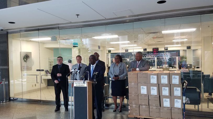 Fulton County tax commissioner Arthur Ferdinand, flanked by other county leaders, announced that tax bills were ready to be sent. The boxes are the bills to be mailed. ARIELLE KASS/AKASS@AJC.COM