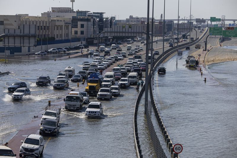 Vehicles drive through standing floodwater caused by heavy rain in Dubai, United Arab Emirates, Thursday, April 18, 2024. The United Arab Emirates attempted to dry out Thursday from the heaviest rain the desert nation has ever recorded, a deluge that flooded out Dubai International Airport and disrupted flights through the world's busiest airfield for international travel. (AP Photo/Christopher Pike)