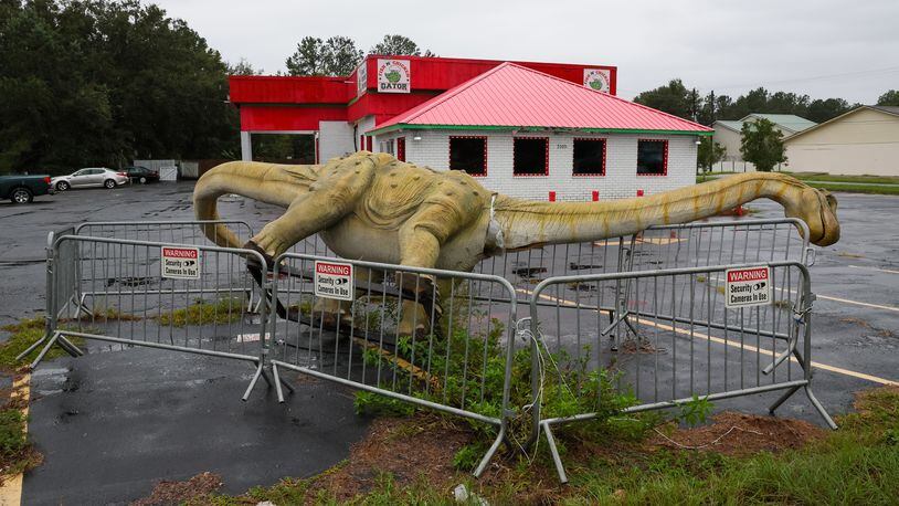 A fallen dinosaur statue is seen in St. Marys on Thursday, September 29, 2022 as tropical storm Ian makes its way north from Florida. (Arvin Temkar / arvin.temkar@ajc.com)