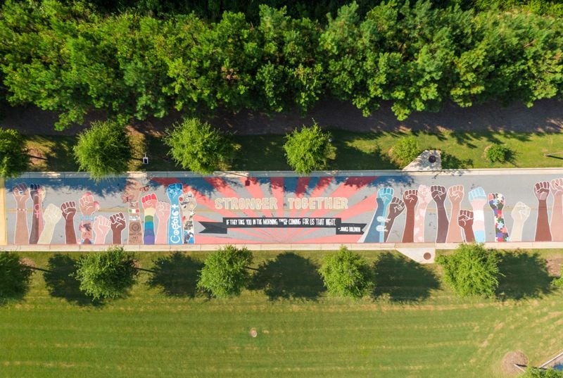 An aerial photo captures a giant colorful mural on the driveway of Drew Charter School Junior/ Senior Academy on Tuesday, Aug. 24, 2021. This side of the mural shows a series of raised fists each representing a marginalized community — LGBTQ, Indigenous Americans, people with autism, women, Asian Americans and Pacific Islanders and Latino communities, etc. — all in solidarity with one another. (Hyosub Shin / Hyosub.Shin@ajc.com)