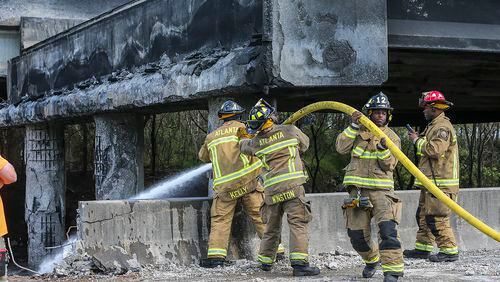 March 31, 2017 Atlanta: Atlanta firefighters remained on the scene putting out a smoldering fire Friday, March 31, 2017 at the I-85 collapse site while construction crews made their way into the zone to begin work. Three people were arrested late Friday in connection with setting the fire. JOHN SPINK /JSPINK@AJC.COM
