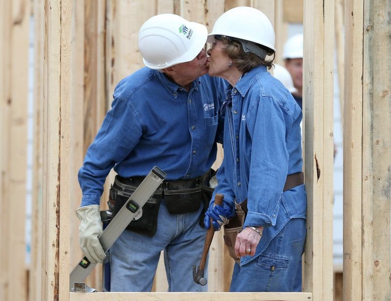 Former President Jimmy Carter sneaks a kiss with Rosalynn while the couple was working on a Habitat for Humanity one-day build on Nov. 2, 2015 in Memphis, Tenn. Nine months later, the Carters returned to Memphis in August 2016 to spearhead a weeklong project to build 19 Habitat houses in the city. AJC FILE PHOTO