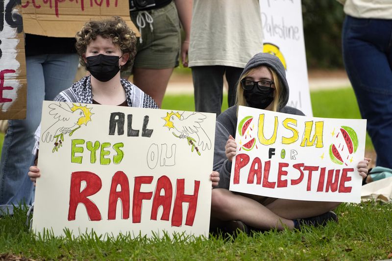 BJ Brumley, left, and fellow University of Southern Mississippi student Vinny Halsey, hold Pro-Palestinian signs protesting the Israel Hamas war in Gaza, during an hour-long silent protest on the school's campus, Tuesday, May 7, 2024, in Hattiesburg, Miss. The group of almost 50 demonstrators drew no counter protesters or hecklers. (AP Photo/Rogelio V. Solis)