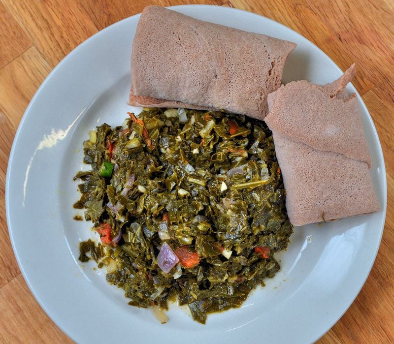 Yohana Solomon, who came to the U.S. from Ethiopia, says Gomen (Collard Greens) will seem familiar to Southern cooks. It’s shown with injera, a fermented flatbread. STYLING BY YOHANA SOLOMON / CONTRIBUTED BY CHRIS HUNT PHOTOGRAPHY