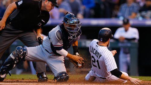 Jonathan Lucroy of the Colorado Rockies slides safely under the tag of catcher Kurt Suzuki of the Atlanta Braves as home plate as umpire Dan Bellino looks on during the second inning at Coors Field Wednesday. Lucroy was called out on the play but the call was reversed after video replay. (Photo by Justin Edmonds/Getty Images)