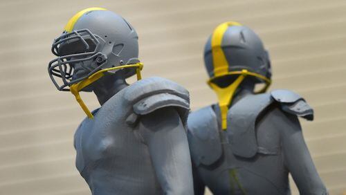 Two small models show how the safety straps might look on the helmet in Aberdeen, Md., on December 8, 2015. The U.S. Army Research Laboratory at Aberdeen Proving Ground is one of three groups working with Under Armour and the NFL to develop a safer football helmet, using straps to allow voluntary movement of the head but provide protection tension under hits. (Lloyd Fox/Baltimore Sun/TNS)