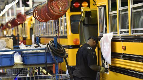 Workers on the Blue Bird Corp. school bus assembly line at the company’s headquarters in Fort Valley, Ga. A new forecast projects 77,600 new jobs in the state this year, down from 103,300 last year. HYOSUB SHIN / HSHIN@AJC.COM