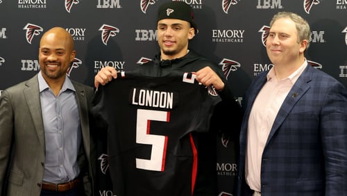 Falcons' 2022 first round NFL draft pick Drake London, center, a wide receiver from USC, holds up his jersey with general manager Terry Fontenot, left, and head coach Arthur Smith, right, at the Falcons Practice Facility April 29, 2022, in Flowery Branch, Ga. (Jason Getz / Jason.Getz@ajc.com)