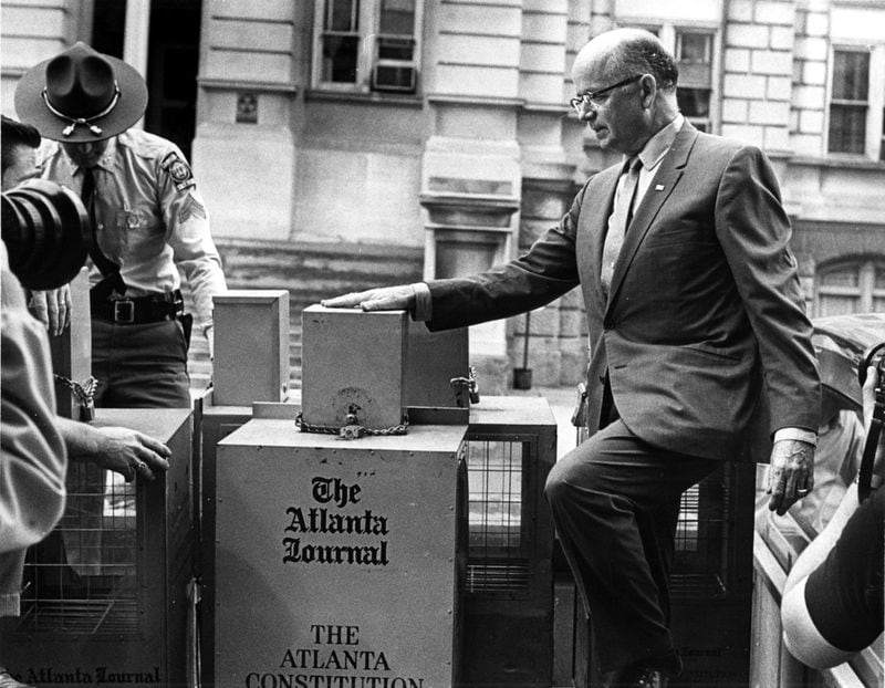 May 29, 1970 - Atlanta, Ga.: Governor Lester Maddox ordered a ban on Atlanta Journal-Constitution vending machines from the state office complex. Gov. Maddox gets a helping hand in removing newspaper racks. He carried out his promise to remove the machines from state property. (Staff photo-Billy Downs) 1970