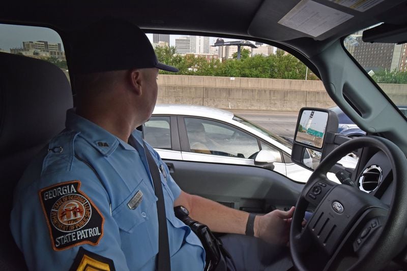 In this June 21 photo, A driver apparently uses a phone while driving as Sgt. First Class Chris Stallings monitors motorists in downtown Atlanta. HYOSUB SHIN / HSHIN@AJC.COM