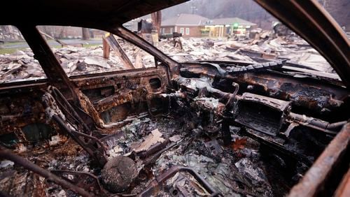 A burned car sits in a parking lot Wednesday, Nov. 30, 2016, in Gatlinburg, Tenn., after a wildfire swept through the area Monday. Three more bodies were found in the ruins of wildfires that torched hundreds of homes and businesses in the Great Smoky Mountains area, officials said Wednesday. (AP Photo/Mark Humphrey)