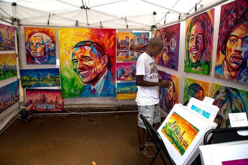 Artist Paul Kyegomb labels his paintings during the ninth annual Piedmont Park Arts Festival on Saturday, August 18, 2018. STEVE SCHAEFER / SPECIAL TO THE AJC