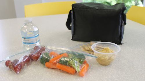 A healthy lunch of hummus, whole-wheat crackers, grapes and bottled water. School lunches ought to provide every student with good nutrition to keep them healthy and learning.