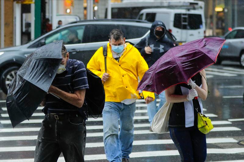 Pedestrians use umbrellas to protect themselves from inclement weather brought about by Tropical Storm Fay, Friday, July 10, 2020, in New York. Beaches closed in Delaware and rain lashed the New Jersey shore as fast-moving Tropical Storm Fay churned north on a path expected to soak the New York City region. (AP Photo/Frank Franklin II)