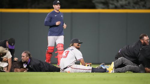 Ronald Acuna ends up on the turf as field guards wrestle down two fans who approached him as he took his spot in the field for the bottom of the seventh inning of a baseball game against the Colorado Rockies, Monday, Aug. 28, 2023, in Denver (AP Photo/David Zalubowski)